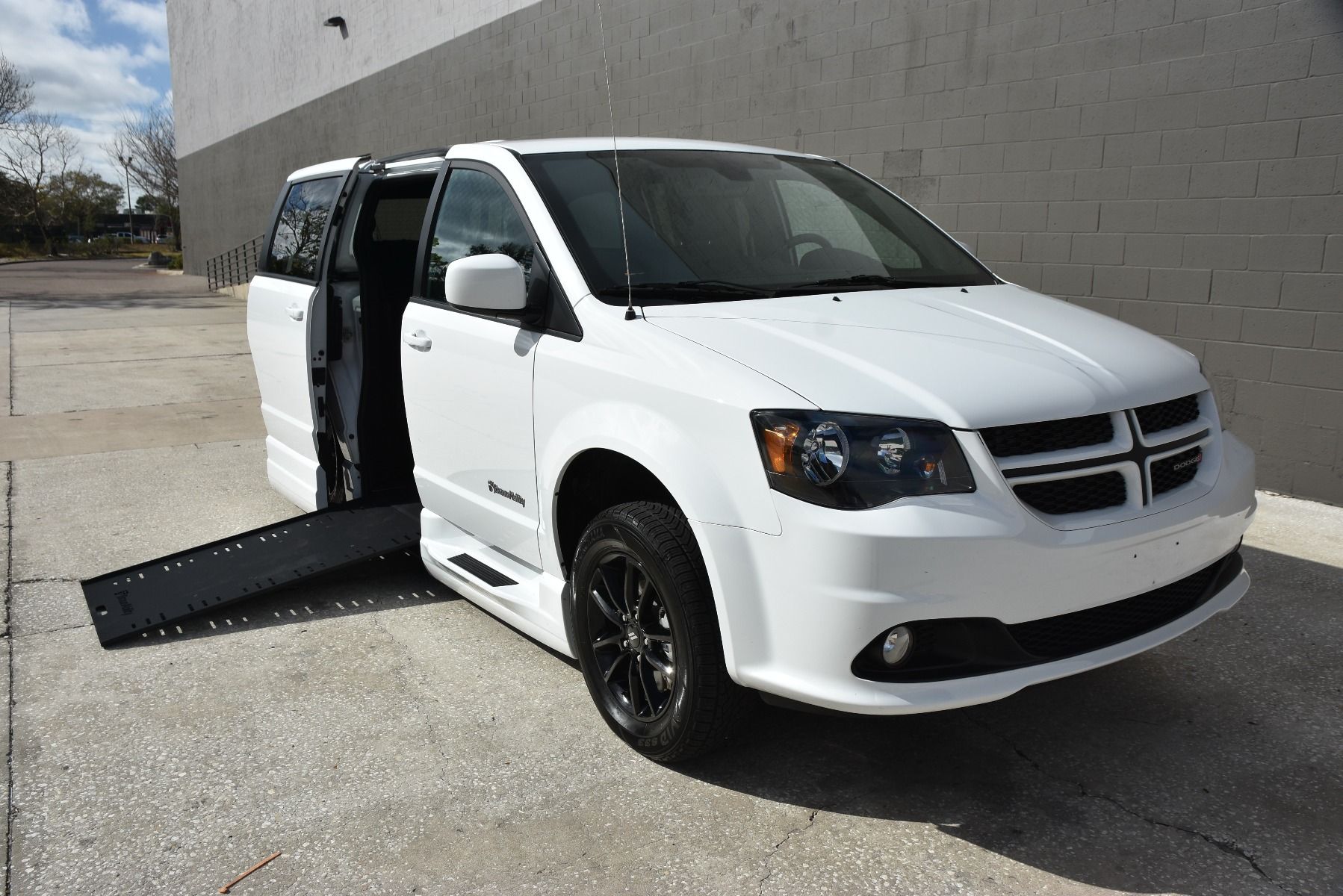 White 2020 Dodge Grand Caravan Wheelchair Van with ramp deployed, as seen from passenger side front angle