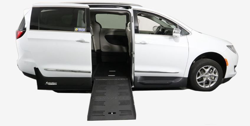 A white Chrysler Pacifica Wheelchair Van with AMS wheelchair van conversion with ramp deployed from open passenger sliding doorway.